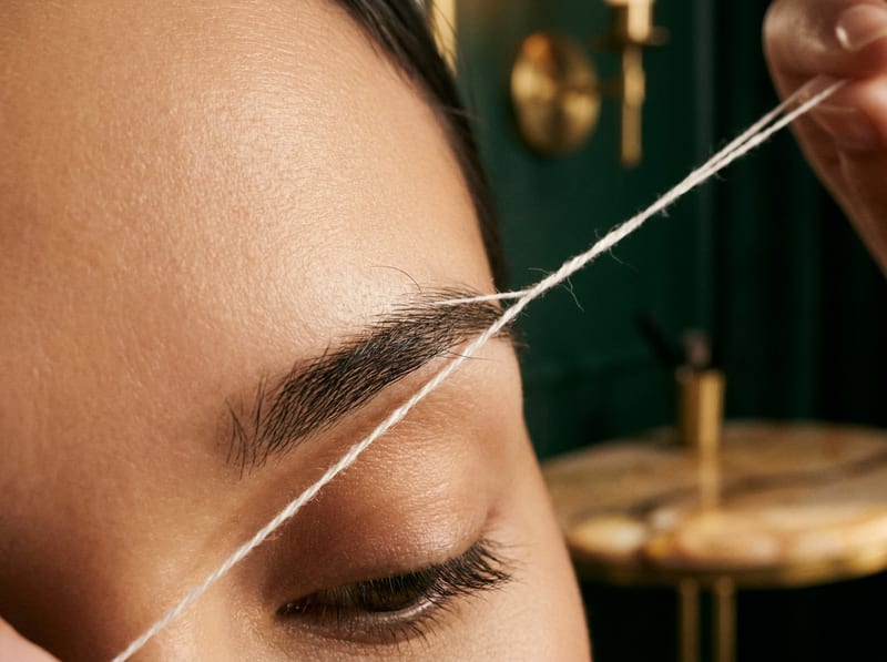 A cotton thread held against a shaped brow.